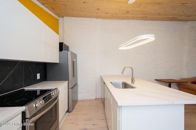 kitchen featuring sink, light wood-type flooring, an island with sink, white cabinetry, and stainless steel appliances