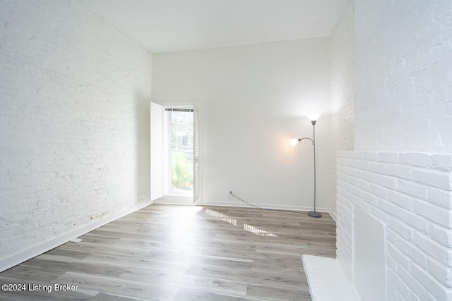 empty room with wood-type flooring and brick wall