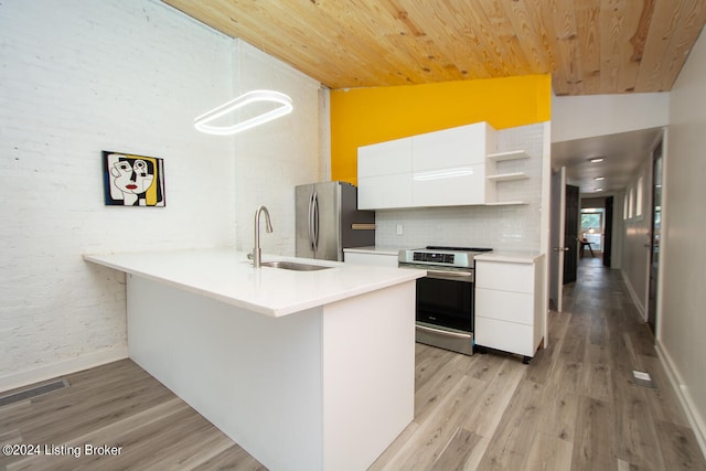 kitchen with white cabinets, stainless steel appliances, kitchen peninsula, and lofted ceiling