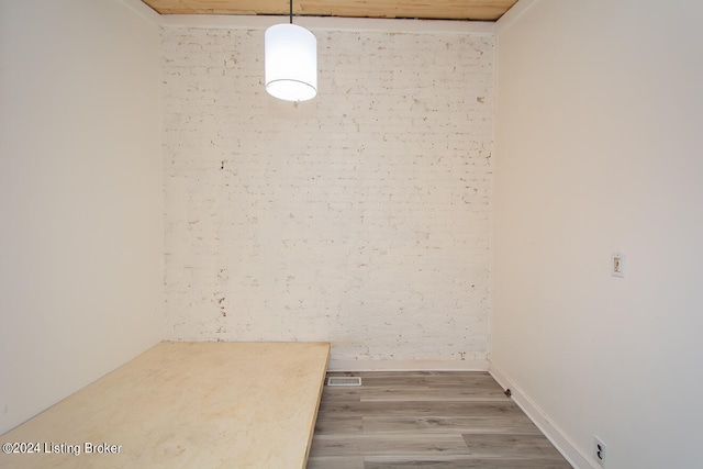 unfurnished dining area featuring hardwood / wood-style floors and brick wall