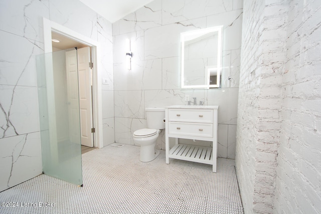 bathroom with vanity, toilet, and tile walls