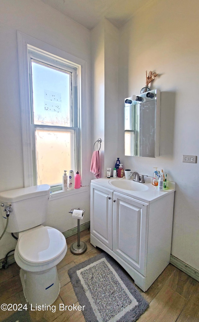 bathroom with toilet, vanity, and hardwood / wood-style flooring