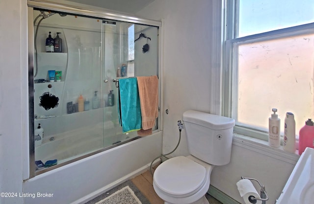 bathroom featuring tile patterned flooring, bath / shower combo with glass door, and toilet