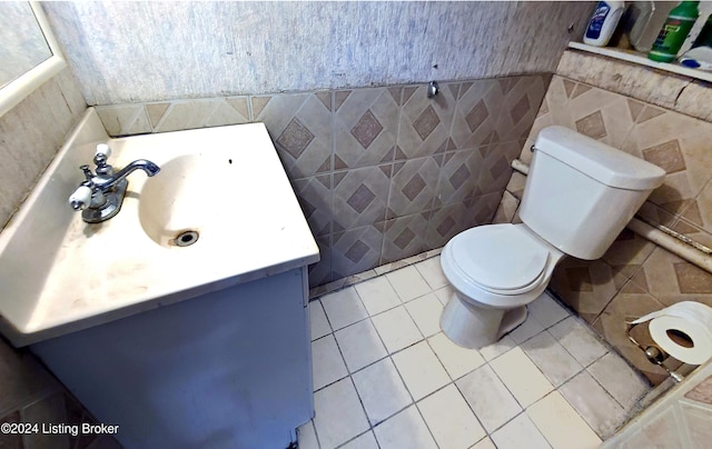 bathroom with tile patterned flooring, vanity, toilet, and tile walls