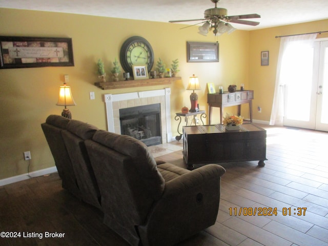 living room with a tile fireplace, wood-type flooring, and ceiling fan