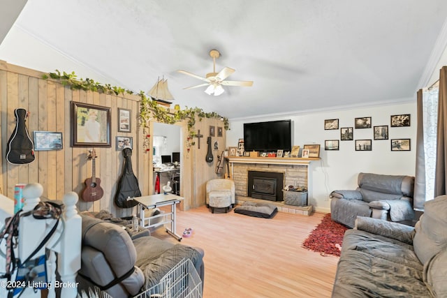 living room featuring a wood stove, ceiling fan, crown molding, wood-type flooring, and vaulted ceiling