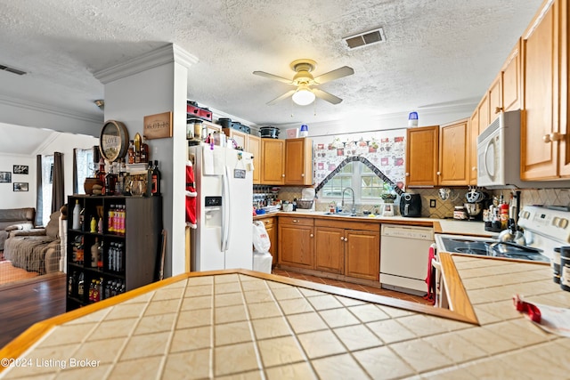 kitchen featuring white appliances, tile countertops, tasteful backsplash, and ornamental molding