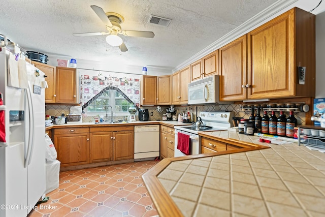 kitchen featuring ornamental molding, white appliances, ceiling fan, sink, and tile counters