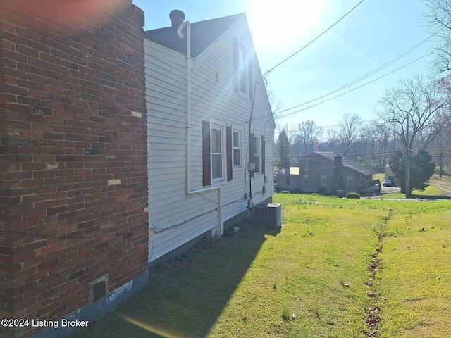 view of side of property featuring a yard and central AC