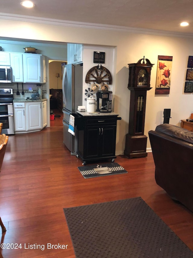 kitchen with white cabinetry, dark wood-type flooring, stainless steel appliances, backsplash, and crown molding