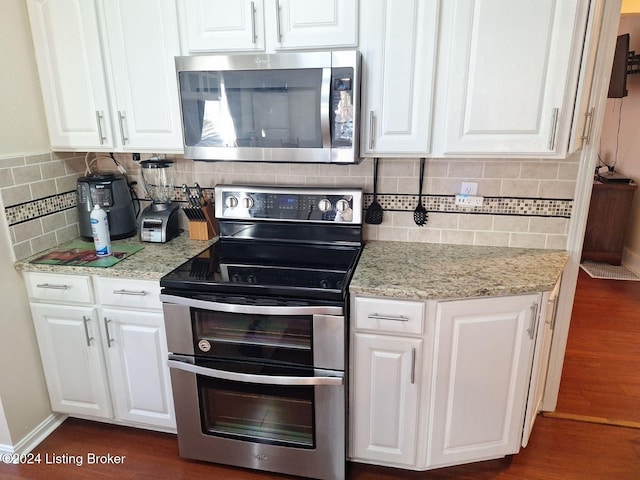 kitchen featuring light stone countertops, dark wood-type flooring, stainless steel appliances, tasteful backsplash, and white cabinets