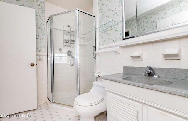 bathroom featuring vanity, toilet, a shower with door, and tile walls