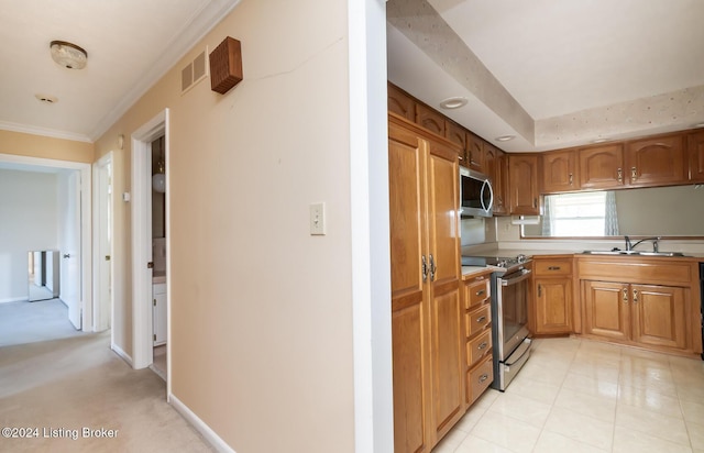 kitchen with stainless steel appliances, light colored carpet, ornamental molding, and sink