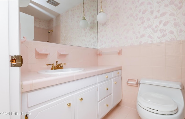 bathroom with tile patterned floors, vanity, tile walls, and toilet