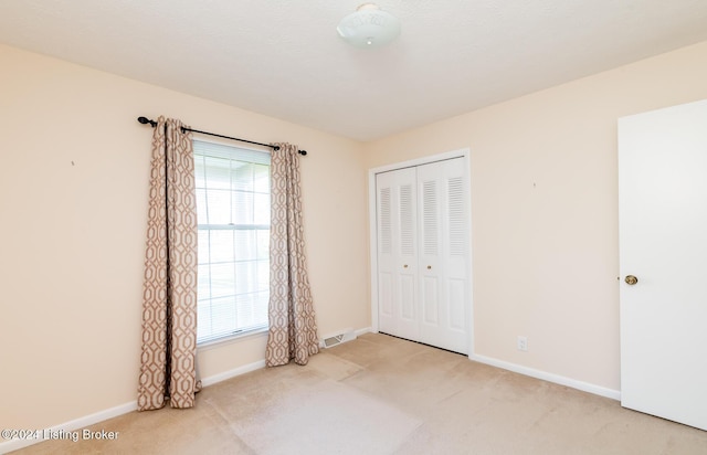 unfurnished bedroom featuring a closet and light colored carpet