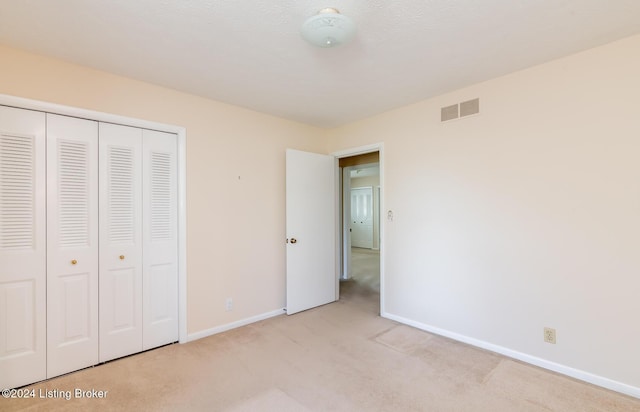 unfurnished bedroom featuring a closet and light colored carpet