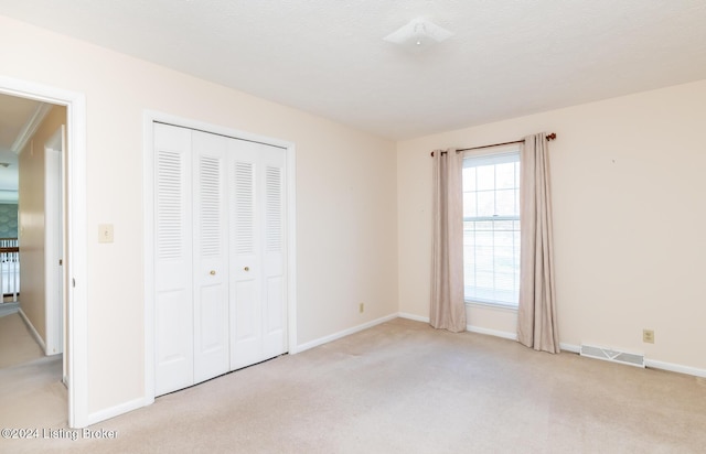 unfurnished bedroom with a textured ceiling, light colored carpet, and a closet