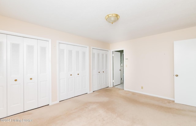 unfurnished bedroom with light carpet and two closets