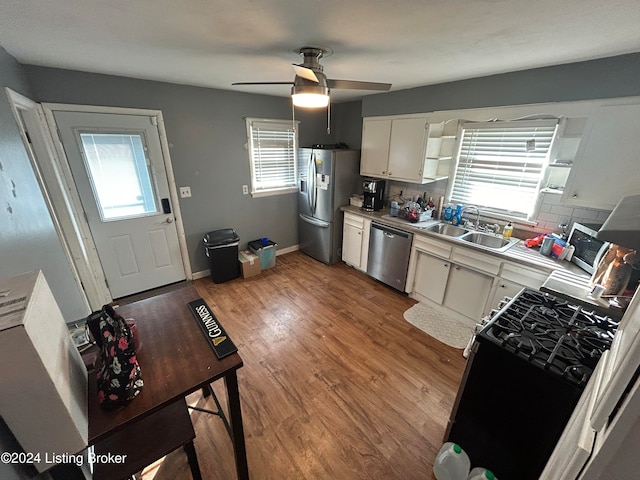 kitchen with white cabinetry, ceiling fan, stainless steel appliances, wood-type flooring, and decorative backsplash