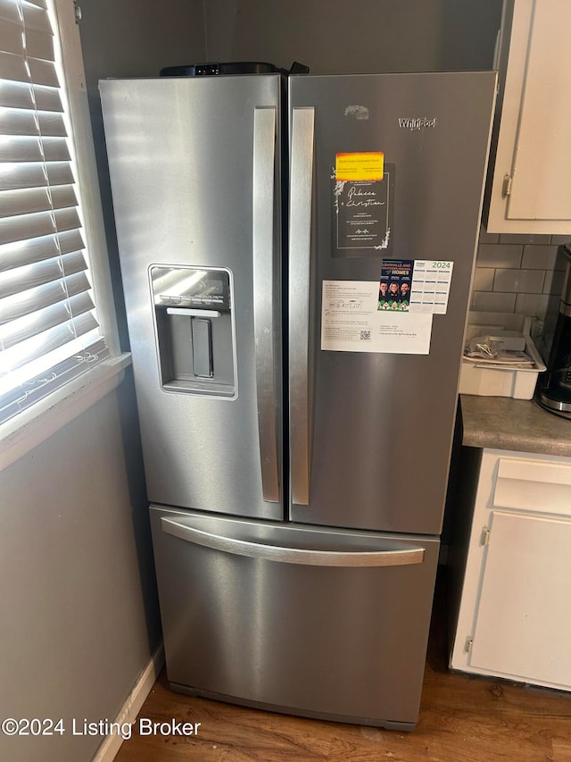 details with stainless steel fridge with ice dispenser, tasteful backsplash, white cabinetry, and hardwood / wood-style floors