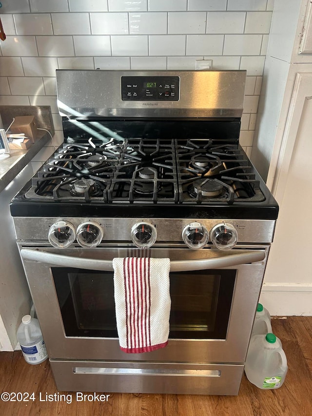 room details with decorative backsplash, hardwood / wood-style floors, and stainless steel gas range