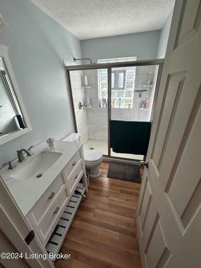 bathroom featuring vanity, hardwood / wood-style flooring, toilet, a textured ceiling, and an enclosed shower