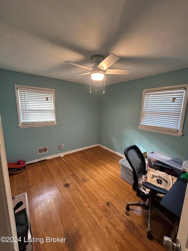 unfurnished office with hardwood / wood-style flooring, ceiling fan, and a healthy amount of sunlight