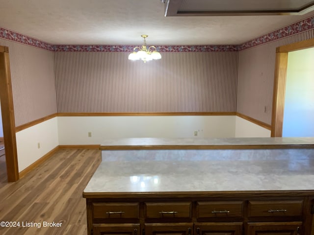 kitchen featuring decorative light fixtures, light hardwood / wood-style floors, dark brown cabinets, and a notable chandelier