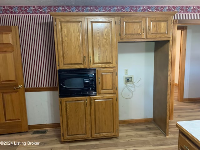 kitchen featuring light hardwood / wood-style floors and black microwave