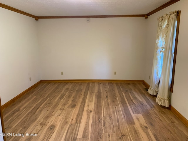 empty room featuring hardwood / wood-style floors and crown molding