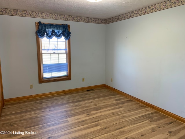 unfurnished room featuring hardwood / wood-style floors and a textured ceiling