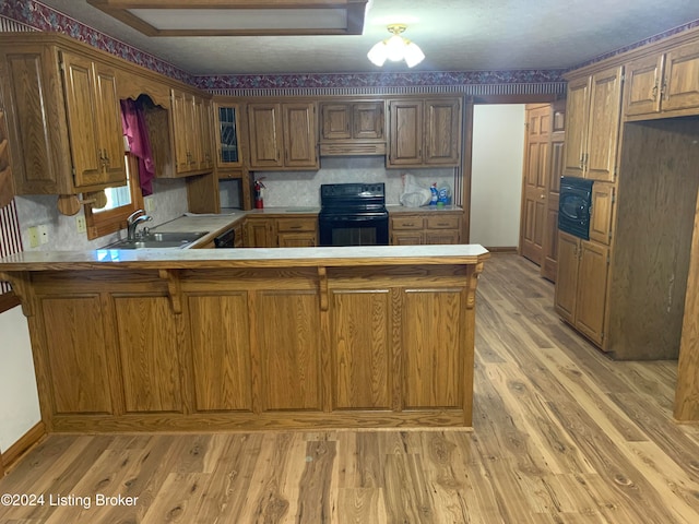 kitchen featuring electric range, light hardwood / wood-style floors, kitchen peninsula, and sink