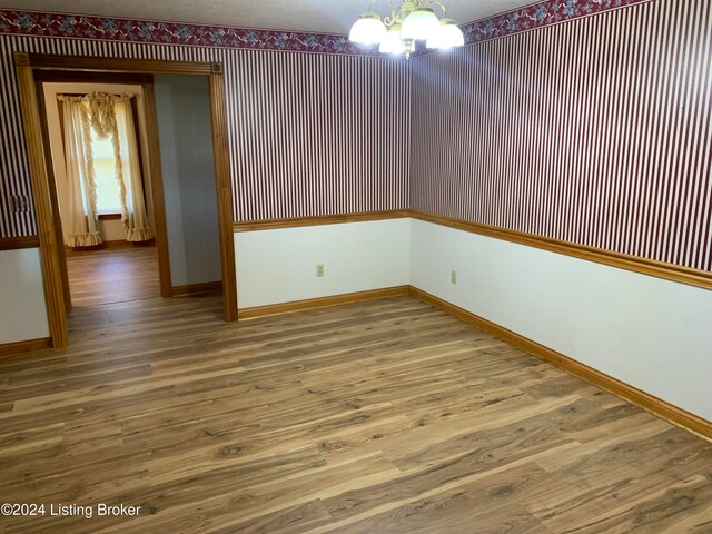 unfurnished room featuring a chandelier and hardwood / wood-style flooring