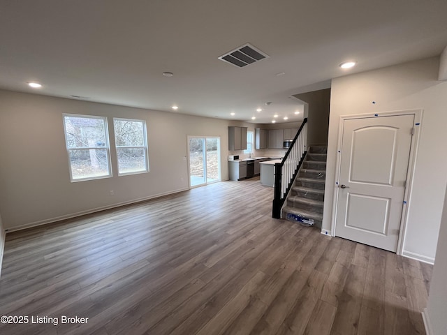 unfurnished living room with recessed lighting, wood finished floors, visible vents, and stairs