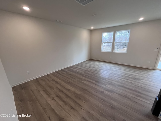 empty room with visible vents, baseboards, dark wood-type flooring, and recessed lighting