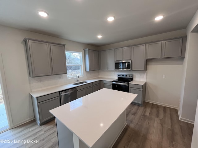 kitchen with backsplash, appliances with stainless steel finishes, gray cabinets, and a sink