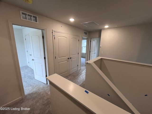 hallway featuring carpet, an upstairs landing, and visible vents