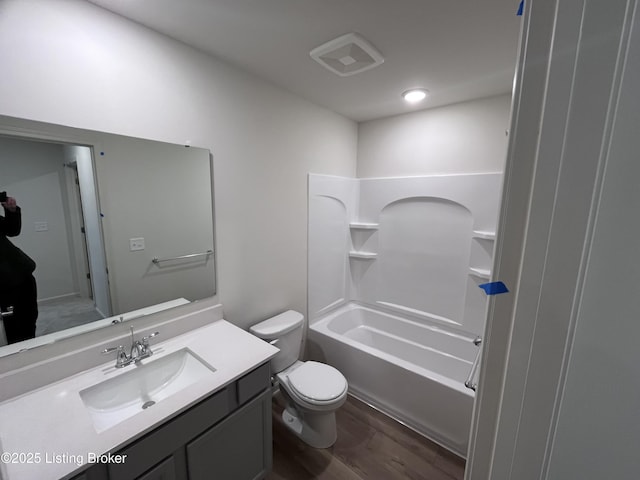 bathroom featuring shower / washtub combination, visible vents, toilet, vanity, and wood finished floors