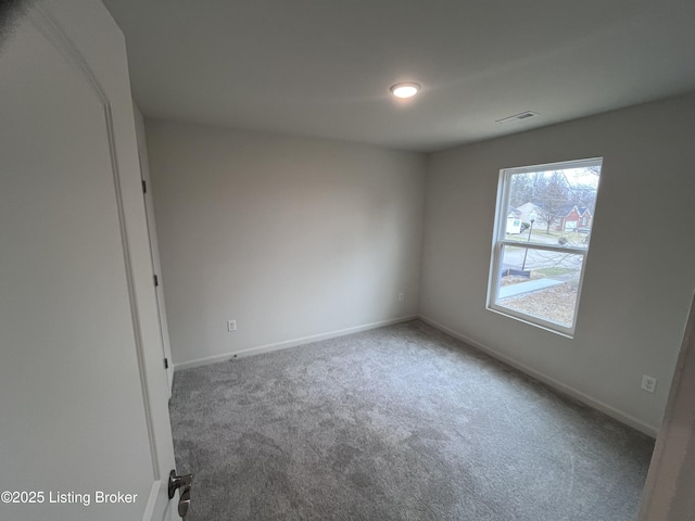 carpeted spare room featuring visible vents and baseboards