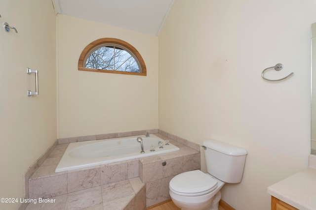 bathroom featuring vanity, toilet, lofted ceiling, and tiled bath