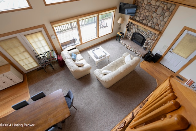 living room featuring high vaulted ceiling, hardwood / wood-style flooring, and a stone fireplace