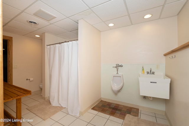 bathroom featuring tile patterned flooring, toilet, a drop ceiling, and sink