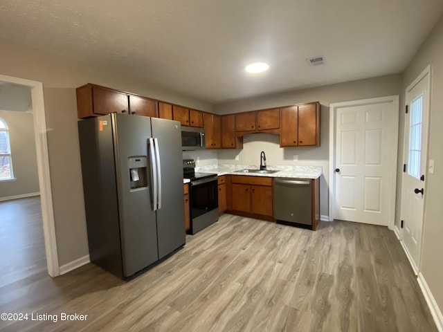 kitchen with light hardwood / wood-style floors, sink, a healthy amount of sunlight, and appliances with stainless steel finishes