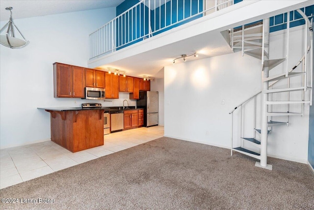 kitchen with a kitchen bar, a towering ceiling, stainless steel appliances, and hanging light fixtures