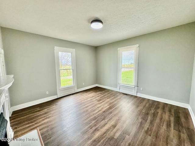 empty room featuring a textured ceiling and dark hardwood / wood-style flooring