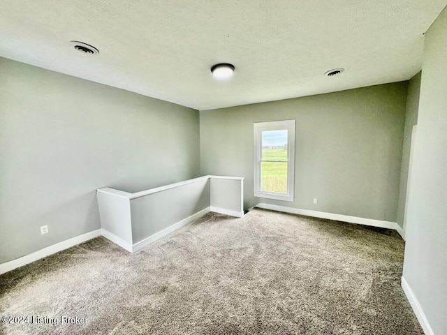 spare room with carpet flooring and a textured ceiling