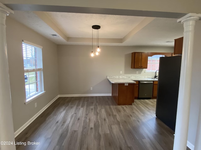 kitchen featuring black fridge, stainless steel dishwasher, a raised ceiling, hardwood / wood-style floors, and hanging light fixtures