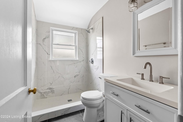 bathroom with tile patterned flooring, vanity, toilet, and tiled shower