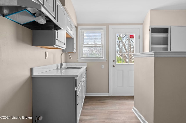 kitchen with gray cabinets, sink, and light hardwood / wood-style flooring