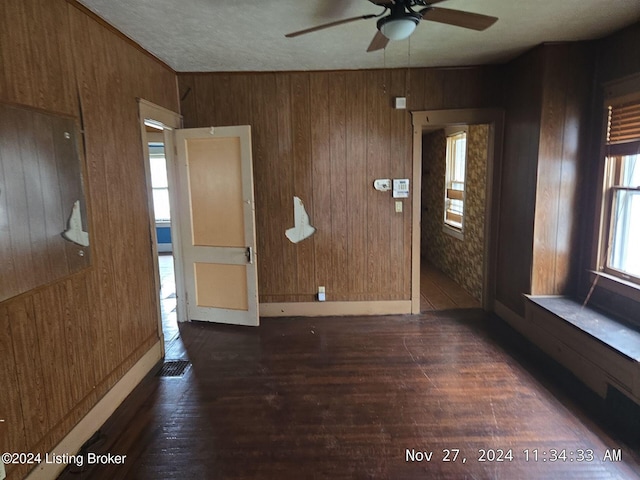 interior space featuring wood walls, ceiling fan, and dark wood-type flooring